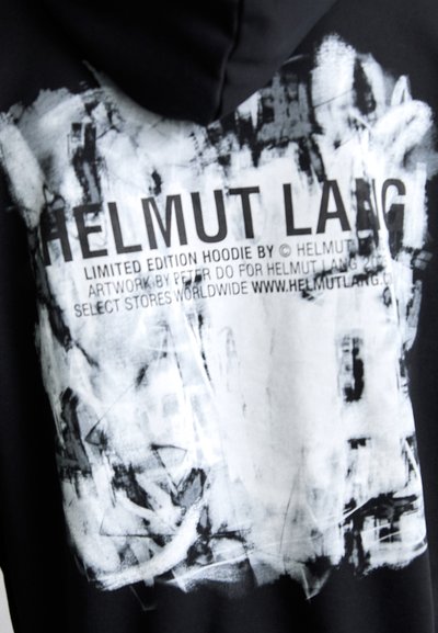 Sudadera negra con un gran gráfico abstracto en blanco y gris, acompañado de texto negro que dice "HELMUT LANG" y detalles sobre la edición limitada.