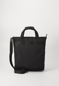 Sac fourre-tout noir en tissu durable avec doubles poignées, bandoulière ajustable, fermeture éclair et logo subtil à l'avant.