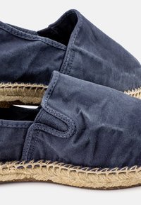 Temno modre platnene espadrile z pletenim jutenim podplatom, ki imajo obliko za obuvanje in šivano detajliranje ob robovih.