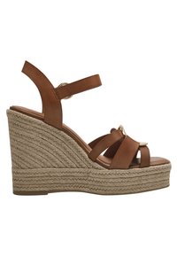 Sandale en cuir marron à talon compensé avec une plateforme en jute tissée, présentant des lanières croisées et un accent décoratif en matériel doré.