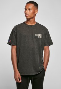 Čierne, oversized tričko s vybledným efektom, na prednej strane so sloganom "TOUCHDOWN SEASON" vytlačeným v krémovej farbe; krátke rukávy, dizajn s okrúhlym výstrihom.