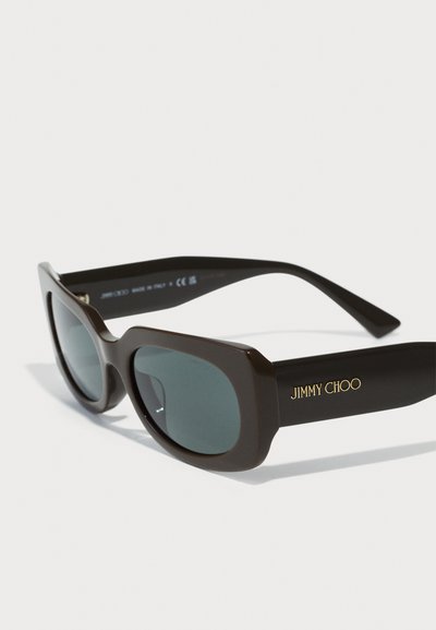 Ochelari de soare maro cu o ramă rectangulară robustă, lentile întunecate și brandul "JIMMY CHOO" în aur pe lateral. Finisaj din plastic neted.