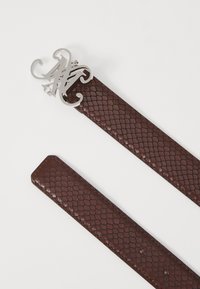 Cintura con una fibbia in argento e una cintura in pelle testurizzata di un bordeaux scuro con motivo a pelle di serpente. Fibbia in argento con dettagli intagliati intricati.