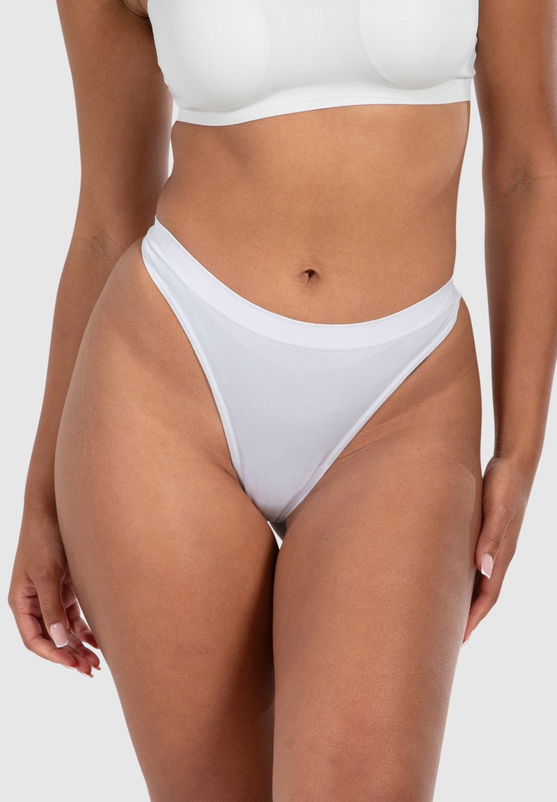 String blanc en coton avec un design taille haute, présentant une texture lisse et une large ceinture élastique. Aucun motif ou accent notable.