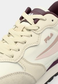 White leather sneaker with burgundy and pale pink accents. Features textured laces and a stitched design, emphasizing sporty aesthetics.