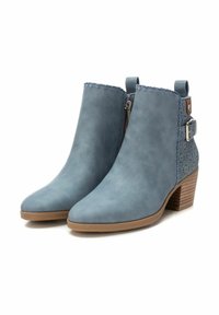Bottes de cheville bleues avec une texture lisse, un bout pointu, une fermeture éclair sur le côté et des découpes décoratives sur le côté. Accent de talon en bois.