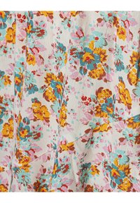 Tissu à surface texturée présentant un motif floral en jaune, turquoise, rose et rouge sur un fond beige clair.