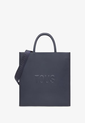 Bolso tote de cuero navy con el logo "TOUS" en relieve, textura suave, asas dobles y una correa desattachable con un patrón de marca.
