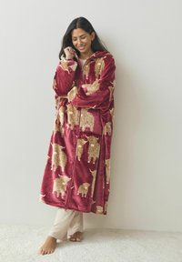 Red plush oversized hoodie with a zipper, featuring a pattern of brown textured sheep. The fabric appears soft and cozy.