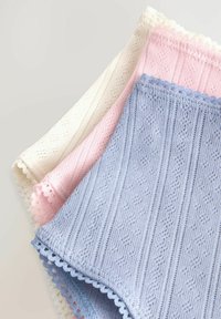 Gebreide katoenen kledingstukken in crème, roze en lichtblauw met textuurpatronen en gegolfde randen. Elk stuk heeft een zachte afwerking.