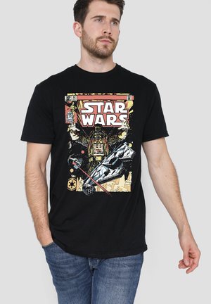 Man wearing black Star Wars t-shirt featuring Darth Vader, a spaceship, and Star Wars logo in retro comic book style.
