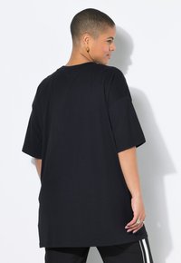 Black oversized t-shirt made from soft fabric, featuring a rounded neckline and short sleeves, with a smooth texture and no visible patterns.