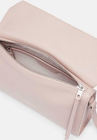 Helle rosa Ledertasche mit strukturiertem Oberflächenfinish, ausgestattet mit einem Reißverschluss und einem passenden Schulterriemen. Das Innere hat eine glatte Oberfläche mit Fächern.
