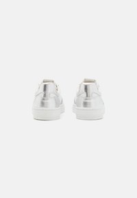 Sneaker metallici argento con texture liscia, suole bianche e dettagli a rilievo discreti. Design low-top, punta rotonda, colletto alla caviglia imbottito.