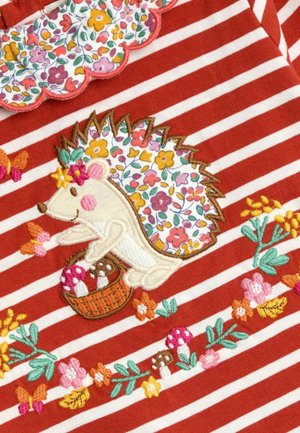 Rot gestreifter Stoff mit gesticktem Igel, der florale Details aufweist, einem Korb mit Pilzen und bunten Schmetterlingen zwischen floralen Akzenten.
