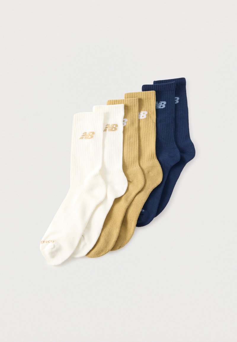 Deux paires de chaussettes montantes côtelées blanches, beiges et bleu marine avec le logo New Balance sur le revers, disposées en chevauchement sur un fond blanc.