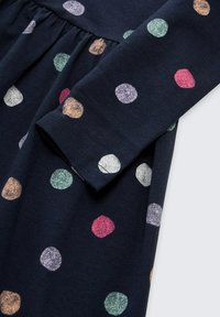 Marineblauwe jurk met lange mouwen, voorzien van kleurrijke, gestructureerde stippen in roze, groen, paars en oranje op een geplooide lijfje.