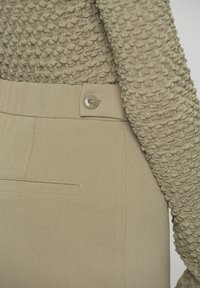 Beige hoge taille broek met een gladde textuur en zijzakken, gecombineerd met een sweater van losse brei in een bijpassende tint.