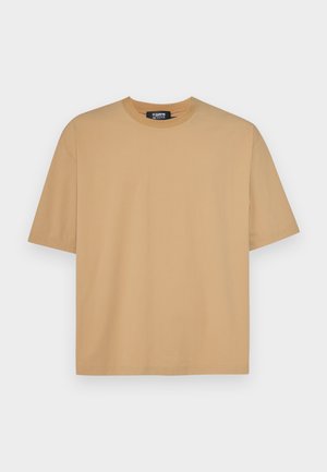 Beżowa bawełniana koszulka z okrągłym dekoltem, krótkimi rękawami i luźnym krojem. Gładka faktura z przeszyciem wzdłuż dołu i rękawów.