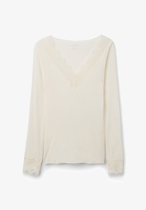 Roomwit top met lange mouwen, V-hals afgezet met kant en bijpassende kanten manchetten, gemaakt van zachte stof.