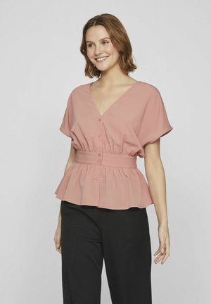 Blouse rose avec un décolleté en V, des manches courtes et un ourlet peplum. Présente des boutons sur le devant et une taille cintrée. Tissu lisse.