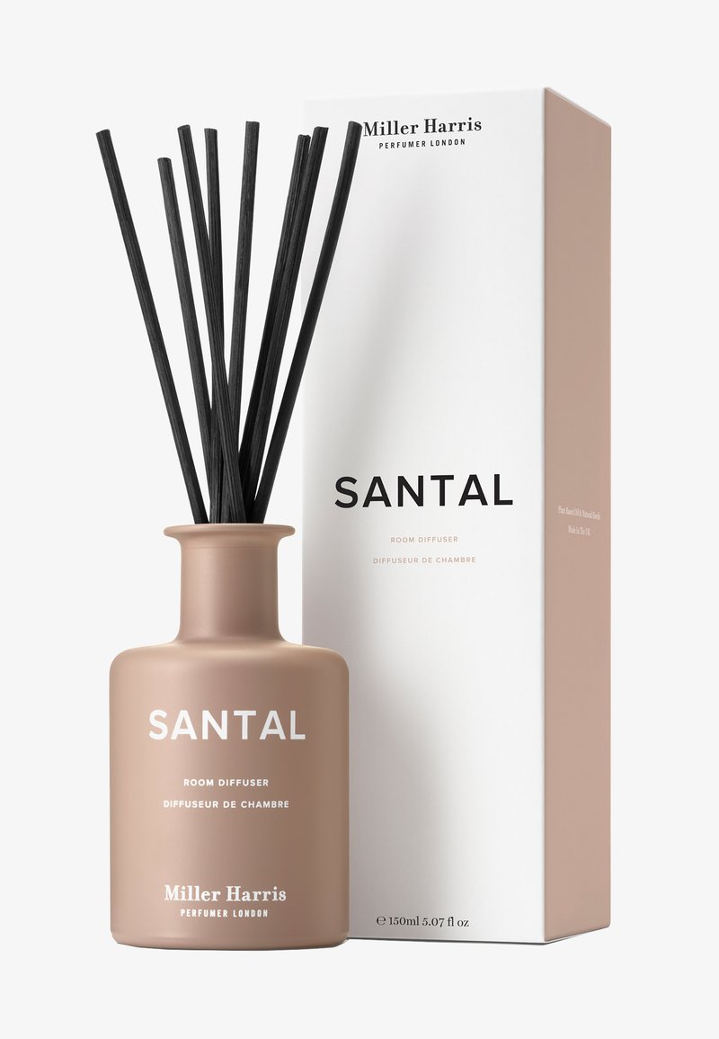 Santal Raumdiffusor in einer matten beigefarbenen Keramikflasche mit schwarzen Rattanruten. Begleitet von einer weißen Box mit minimalistischen Texten und Branding.