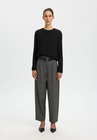 Black long-sleeve top paired with gray, wide-leg trousers featuring a subtle pattern, cinched at the waist with a black belt, and black pointed heels.