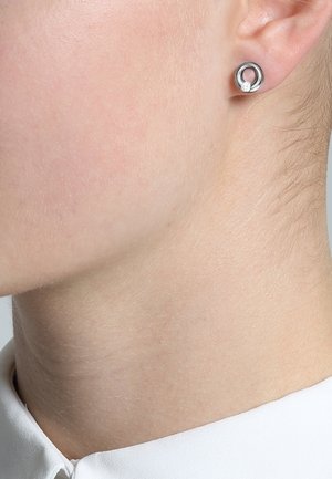 Boucles d'oreilles circulaires en argent avec un petit accent de pierre précieuse, présentant une finition polie et une texture lisse, conçues pour un look contemporain.