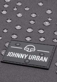 Čierna textilná látka s kvapôčkami vody a obdĺžnikovou nášivkou s nápisom "JOHNNY URBAN" v bielom a šedom písmene.
