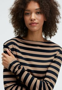 Gestreiftes Langarmshirt in Beige und Marineblau, mit einem Bootsausschnitt und weichem Stoff, mit enganliegenden Ärmeln und einer lockeren Passform.