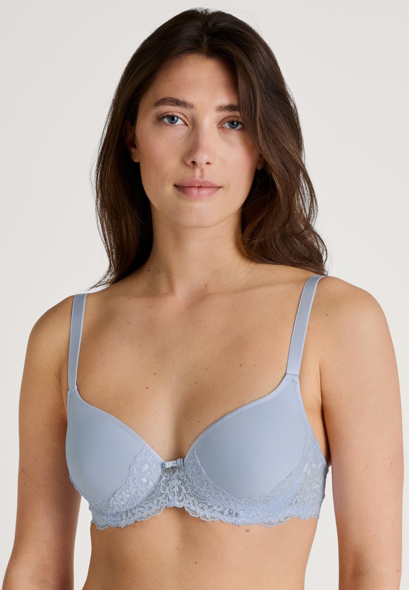 Soutien-gorge bleu clair avec des bonnets lisses et une garniture en dentelle. Les bretelles ajustables et un délicat accent en dentelle au niveau de la bande ajoutent de la texture et du détail.