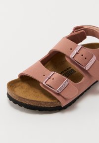 Rosa Birkenstock-liknande sandal med två justerbara breda remmar, metallspännen, korkfotbädd och en texturerad gummisula.