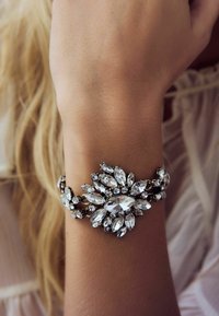 Sjanseći narukvica s cvjetnim dizajnom koja sadrži prozirne rhinestone i metalnu podlogu, ističući miks marquise i okruglih oblika.