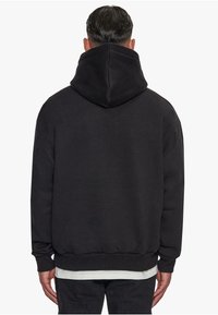 Schwarzer Kapuzenpullover mit lockerem Schnitt, gerippten Bündchen und Saum. Weiche Textur, minimalistisches Design und große Kapuze.