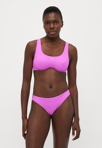 Ružový športový bikini set so štruktúrovaným dizajnom. Vrchný diel má štvorcový výstrih, zatiaľ čo spodný diel je nízko posadený s jednoduchým strihom.