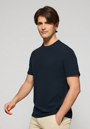 Marineblauwe T-shirt met korte mouwen, ronde hals, ribbelstructuur en een klein logo op de borst. Glad materiaal en een casual pasvorm.