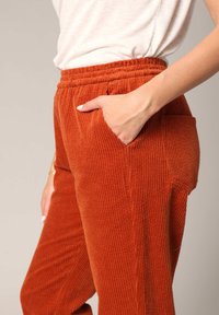 Roodbruin corduroy broeken met verticale ribbels en een elastische tailleband. Voorzien van zijzakken en een ontspannen pasvorm.