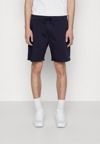 Shorts de bain bleu marine avec une taille élastique, cordon de serrage et poches latérales ; fabriqués en tissu léger et avec une coupe décontractée.