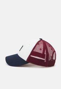 Baseballcap med hvit front, marineblå brem og burgunder nettbakside. Har brodert detaljer på frontpanelet og ventilasjonsåpninger.