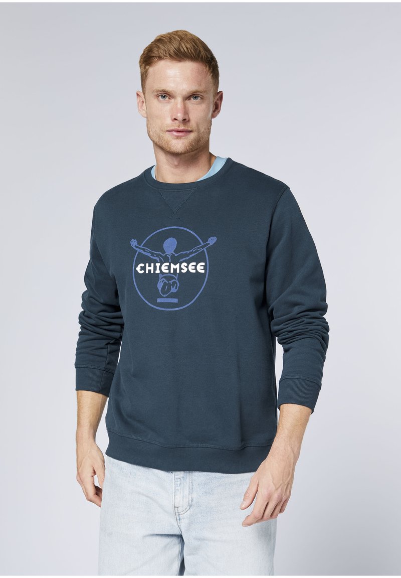 Navy crewneck sweatshirt featuring a large printed logo in blue and white, with long sleeves and ribbed cuffs. Smooth texture, casual fit.