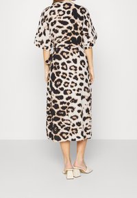 Vestido midi de estampado de leopardo con mangas sueltas, cintura ceñida y tela fluida. Presenta un patrón en tonos beige, negro y marrón.