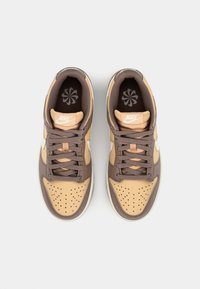 Nike sportcipők világosbarna és barna színkombinációval, perforációkkal, texturált anyagokkal, valamint párnázott nyelv- és gallérkialakítással.