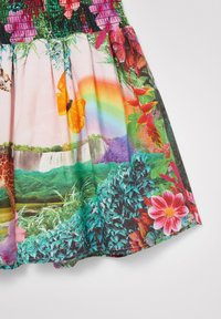 Buntes Kleidungsstück mit einem lebhaften Landschaftsdruck, der Blumen, Grünflächen, Wasserfälle und Tiere umfasst. Das Material wirkt leicht und fließend.