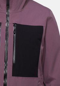 Lila wasserdichte Jacke mit einem schwarzen Einsatz, hohem Kragen und einem Frontreißverschluss mit schwarzen Ziehschlaufen. Glatte Textur mit matter Oberfläche.