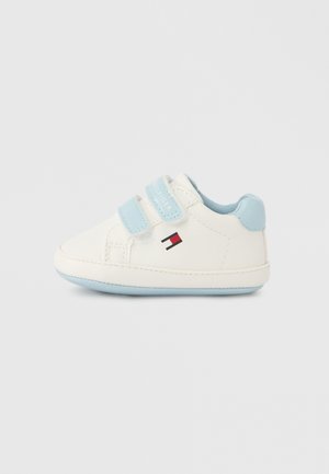 Biała dziecięca trampka z jasnoniebieskimi akcentami. Posiada dwa paski na rzep, gumową podeszwę oraz małe logo z czerwono-niebieskimi detalami.