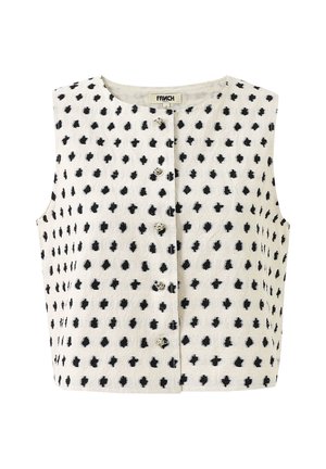 Mouwloos wit cropped top met zwarte onregelmatige polkadots en een knoopsluiting aan de voorkant.