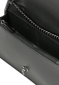 Interno di una borsa in pelle nera con hardware argentato, dotata di una tasca con zip e un accento a catena lungo il bordo superiore. Texture liscia in tutto.