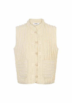 Kremna telovnik iz teksturirane tkanine z navpičnimi črtami. Ima mandarin ovratnik, gumbe spredaj in dva stranska žepa.