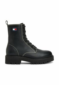 Bota de combate negra de cuero con cordones, suela gruesa, costuras blancas, tirador en el talón y pequeño parche del logo de Tommy Jeans en el costado.