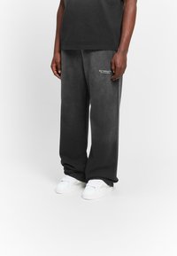 Gray sweatpants with a relaxed fit, featuring an embroidered "RETERNITY" logo on the left thigh. Paired with white sneakers.